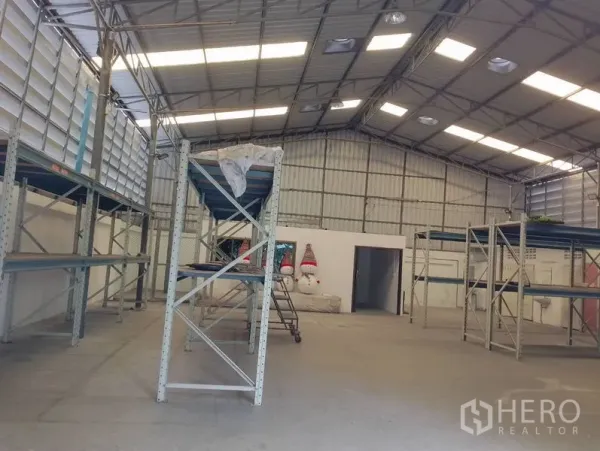 Warehouse for rent in Huai Khwang, Bangkok - Spacious warehouse hall featuring steel trusses, skylights and multiple pallet racks.