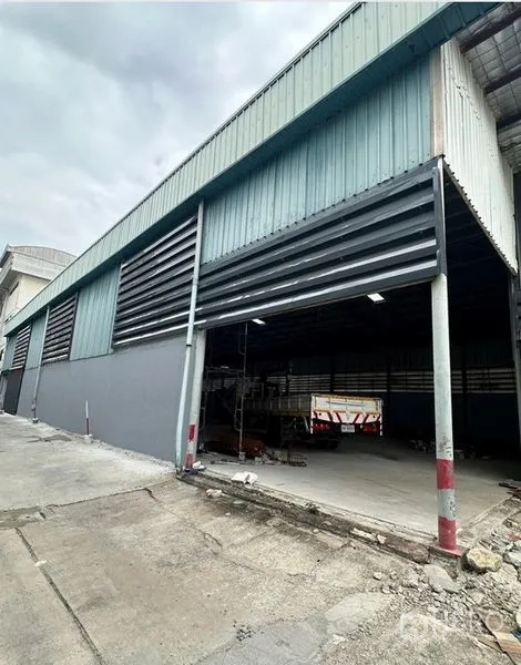 Warehouse for rent in Suan Luang, Bangkok - Metal-clad warehouse exterior in Suan Luang with open sliding loading door and driveway.