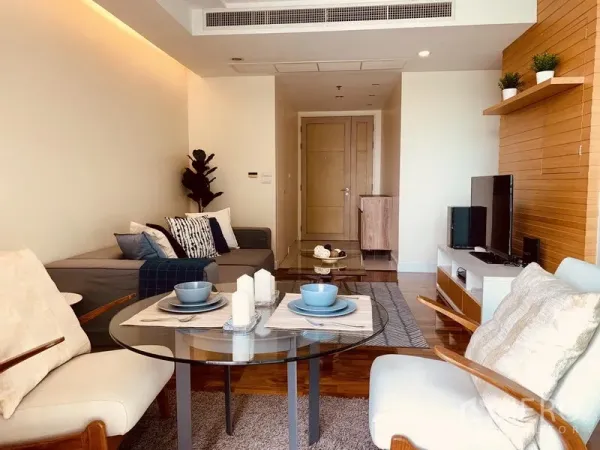Condominium for rent in Watthana, Bangkok - Bright Sukhumvit-area condo living room with glass dining table, built-in TV wall and warm wooden floors.