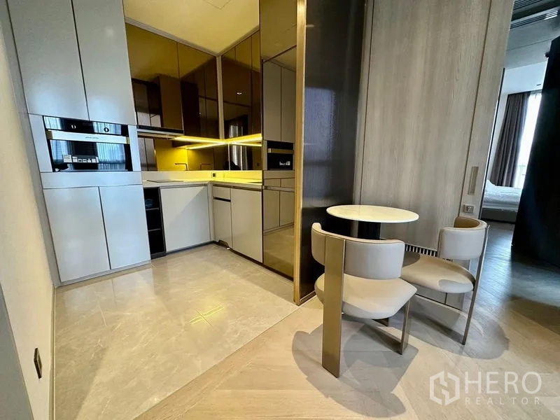 Condominium for rent - Modern kitchen with built-in appliances, glossy cabinetry, under-cabinet lighting, and a round two-seat dining table.