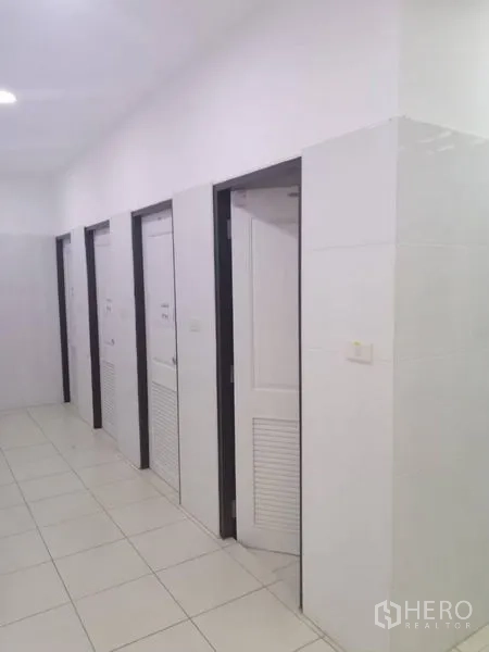 Warehouse for rent in Bang Phli, Samut Prakan - Clean restroom corridor with multiple white stall doors and tiled walls.