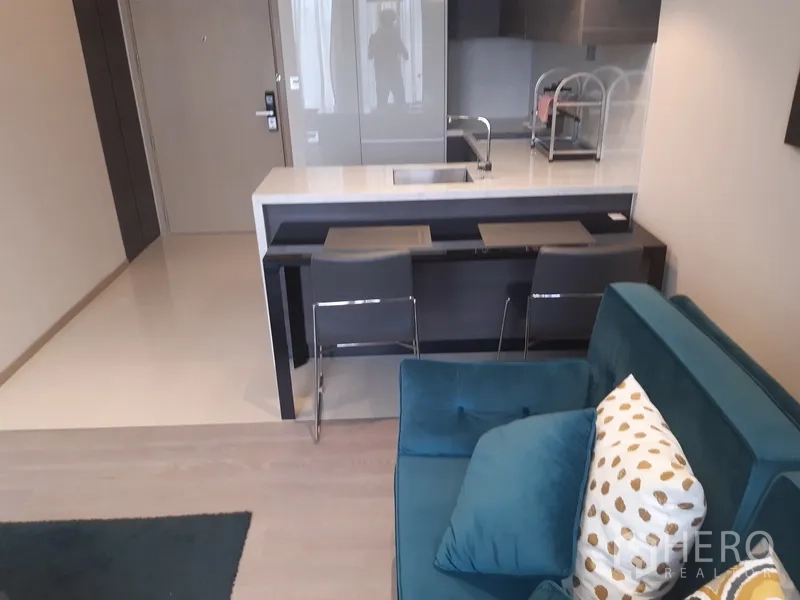 公寓 出租或出售在Watthana, Bangkok - 沙发布置在吧台旁，双高脚椅与石面中岛，布局紧凑。