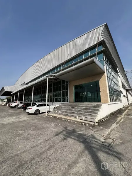 โรงงาน ให้เช่าหรือขายในSai Noi, Nonthaburi - ภาพด้านหน้าโรงงานสมัยใหม่ ผนังเมทัลชีทพร้อมสำนักงานกระจกและที่จอดรถ
