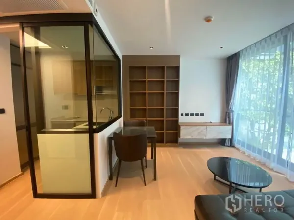 Condominium for rent in Watthana, Bangkok - Open-plan living and dining area with glass kitchen enclosure and sheer curtains.