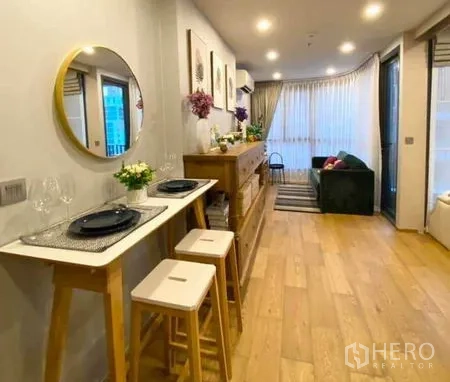 公寓 出售在Ratchathewi, Bangkok - 开放式餐客区，木地板、大面积窗帘墙与舒适沙发。