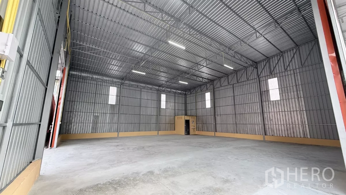 Warehouse for rent in Wang Thonglang, Bangkok - Large warehouse interior showing high ceiling, LED lighting, and a rear utility room.