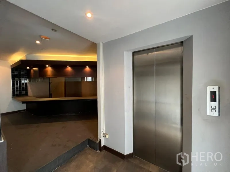 Shophouse for sale in Bang Rak, Bangkok - Passenger elevator opening onto a floor with bar area and downlights.