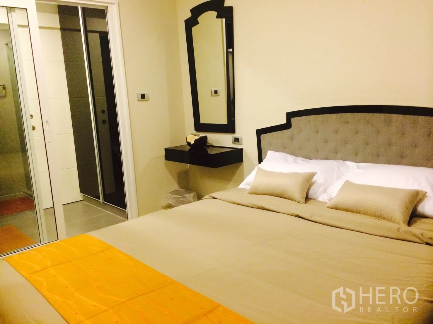 Condominium for rent in Khlong Toei, Bangkok - Cozy bedroom with upholstered headboard and sliding door to the bathroom.
