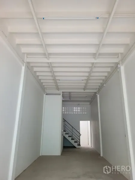 Shophouse for rent in Khlong Toei, Bangkok - Long, freshly painted ground floor with exposed beams and fluorescent lighting.