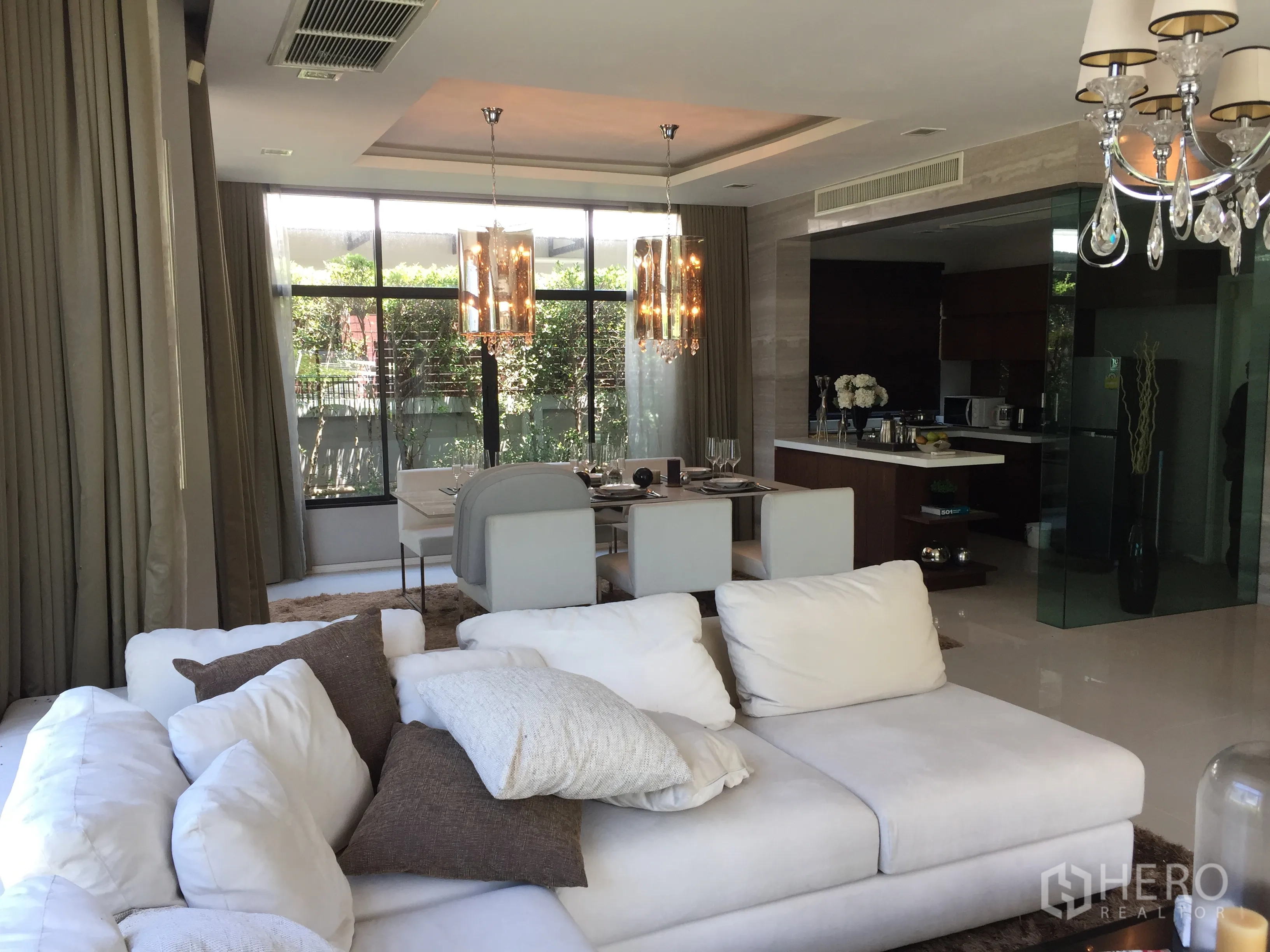 Detached House for sale in Prawet, Bangkok - Bright open-plan living and dining area with large windows and chandelier lighting.