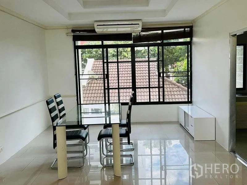 Home Office for rent in Watthana, Bangkok - Dining area with glass table and four chairs next to wide windows and air conditioning.