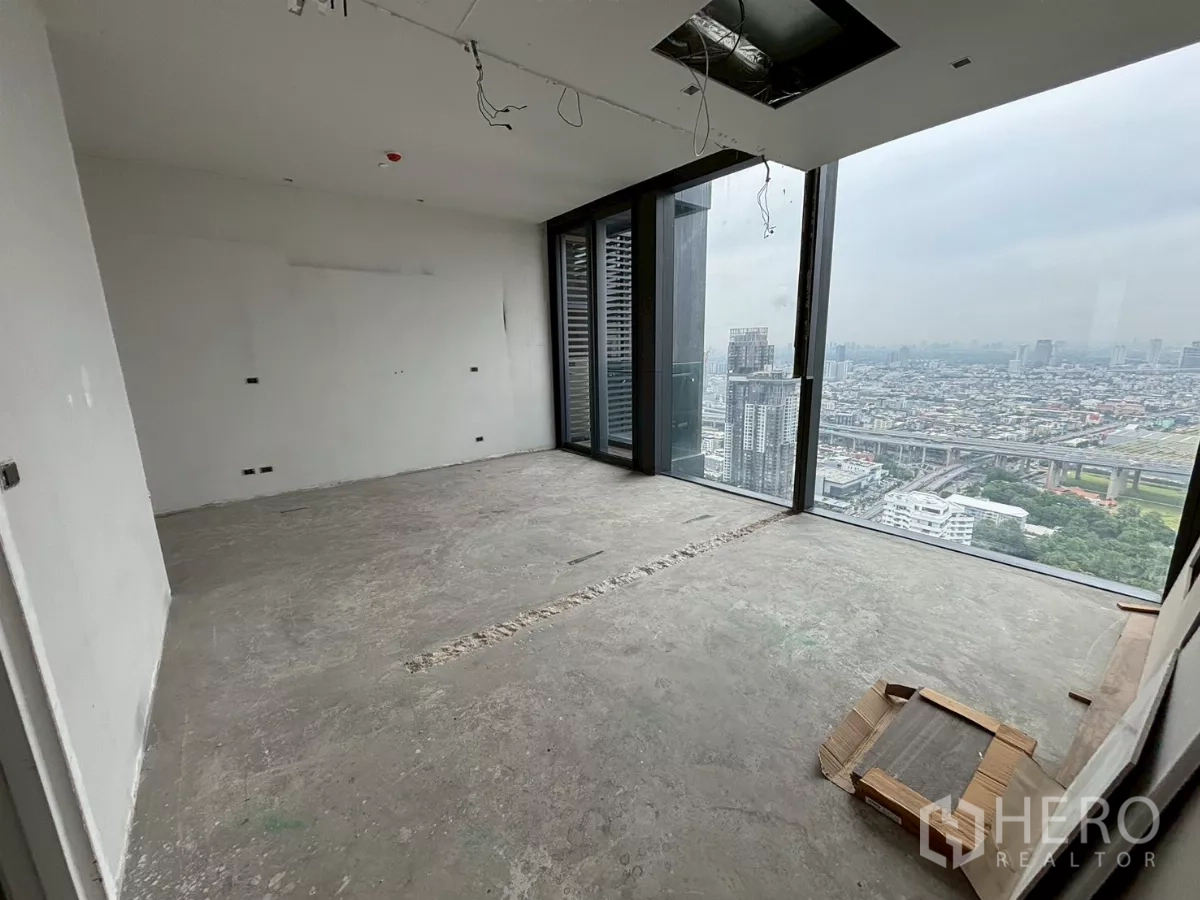 Condominium for sale in Bang Kho Laem, Bangkok - Bare-shell room with exposed ceiling services and broad skyline vistas.