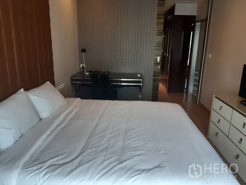 公寓 出租在Bangkok - 卧室另一角可见书桌、衣柜与床边抽屉柜。