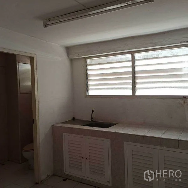 Shophouse for rent in Khlong Toei, Bangkok - Simple pantry with countertop sink, louvered window and adjoining bathroom.