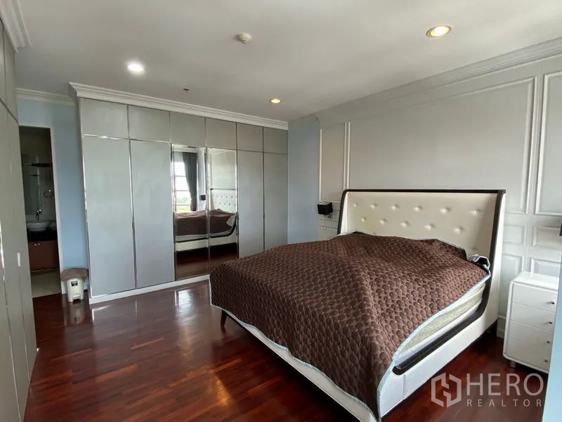 Condominium for rent in Ratchathewi, Bangkok - Master bedroom with mirrored wardrobes, upholstered bed, and ensuite access.
