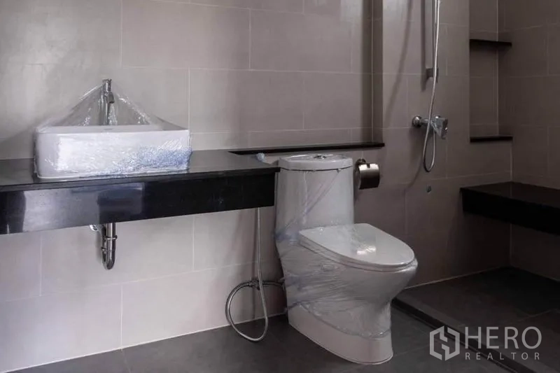 Home Office for rent or sale in Lak Si, Bangkok - Tiled bathroom with shower, toilet and a long countertop basin.
