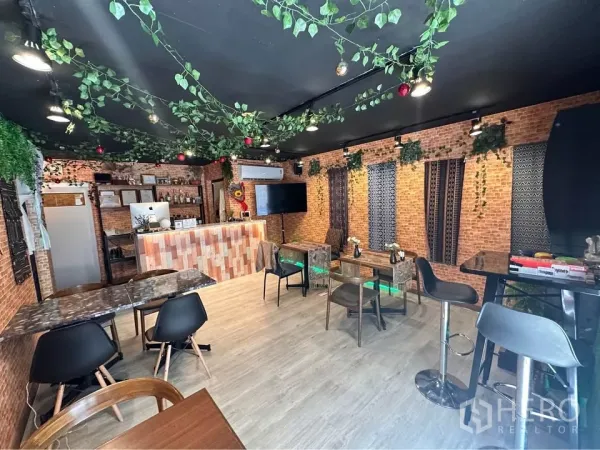 Retail Space for rent in Watthana, Bangkok - Cozy café-style retail interior with brick walls, a service bar counter, and mixed seating under decorative greenery.
