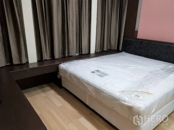 Condominium for rent in Khlong Toei, Bangkok - Spacious master bedroom with king bed, wood floors and built-in ledge by the window.