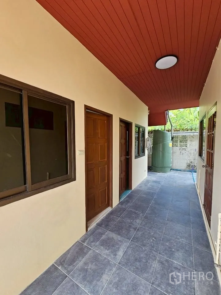 带办公室的家 for rent in Wang Thonglang, Bangkok - 后侧走廊，红色天花，多扇门窗，尽头可见水箱。