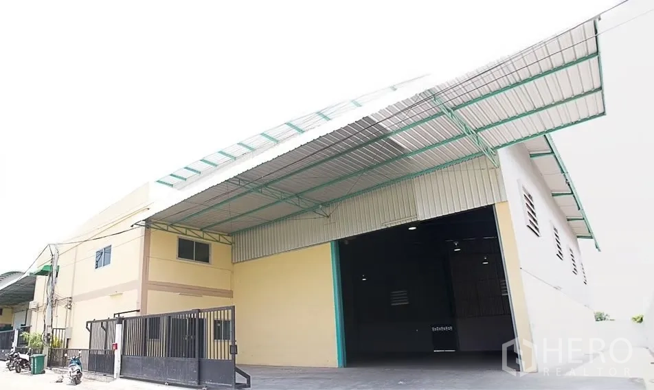 คลังสินค้า ให้เช่าในPathum Thani - ด้านหน้าโกดัง ประตูม้วนกว้าง หลังคาคลุมลานโหลด และประตูรั้วความปลอดภัย