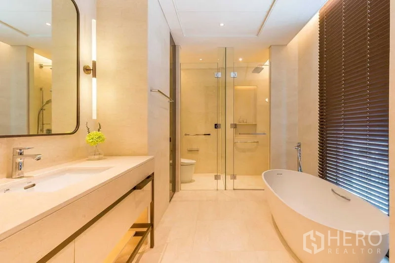Condominium for sale in Pathum Wan, Bangkok - Luxury bathroom with freestanding bathtub, glass shower and long vanity with mirror
