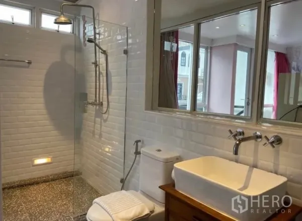 Townhouse for rent in Khlong Toei, Bangkok - Spacious bathroom with glass shower, white tiles and large vanity.