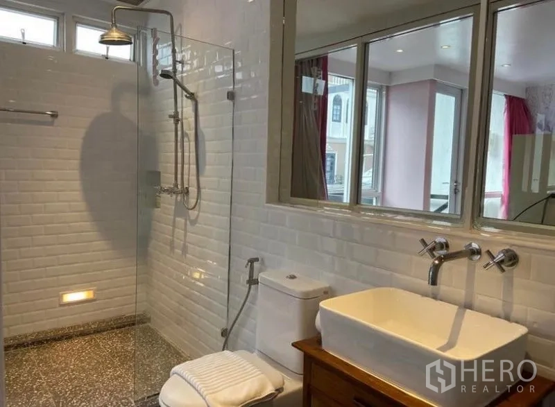 Townhouse for rent in Khlong Toei, Bangkok - Spacious bathroom with glass shower, white tiles and large vanity.