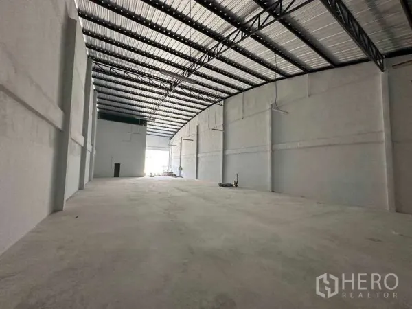 Warehouse for rent in Samut Sakhon - Spacious clear-span storage hall with arched metal roof and light coming from the entrance.