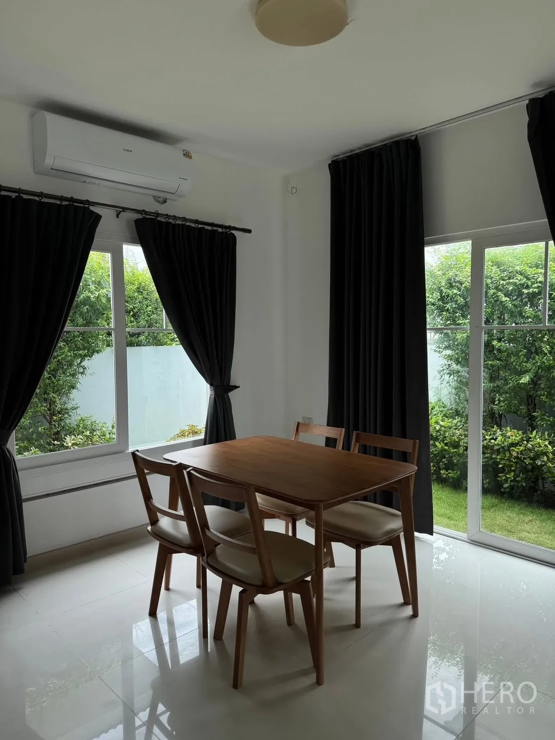 Detached House for rent in Bang Phli, Samut Prakan - Dining area with wooden table and chairs facing the garden through sliding doors.