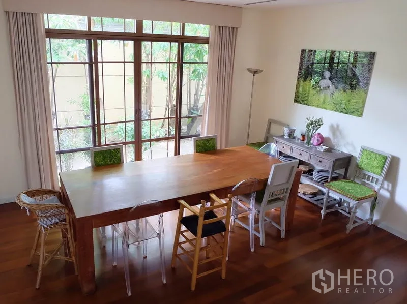 บ้าน ให้เช่าในWatthana, Bangkok - โซนรับประทานอาหาร โต๊ะไม้ยาว เก้าอี้หลากสไตล์ และหน้าต่างสูงเต็มบานรับวิวสีเขียว