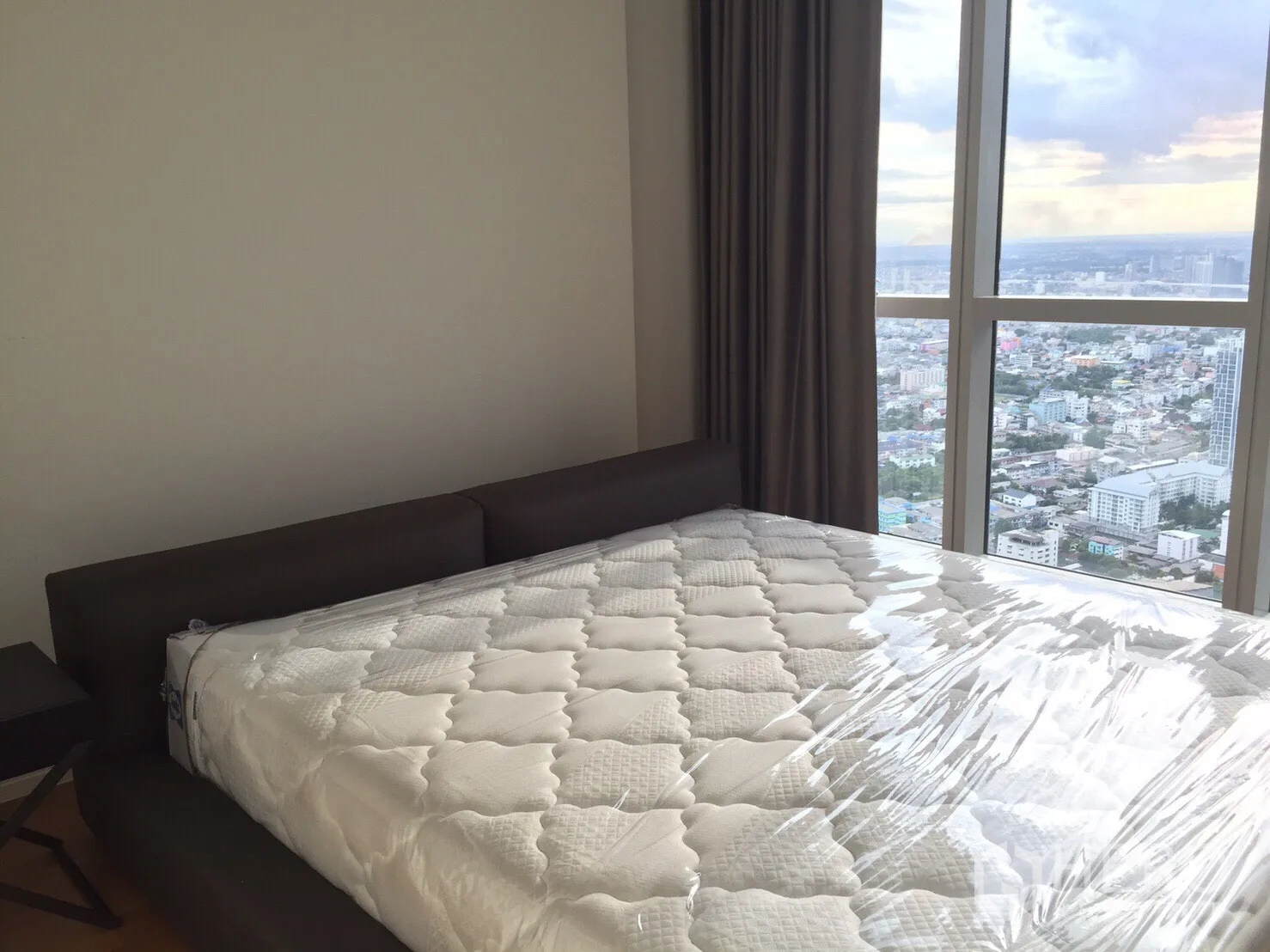 Condominium for rent or sale in Khlong San, Bangkok - Master bedroom with large window and sweeping skyline and river views.