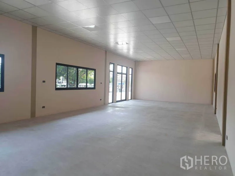 货栈 出租在Chachoengsao - 仓库园区内明亮的办公室空间，吊顶、大片窗户与玻璃门。