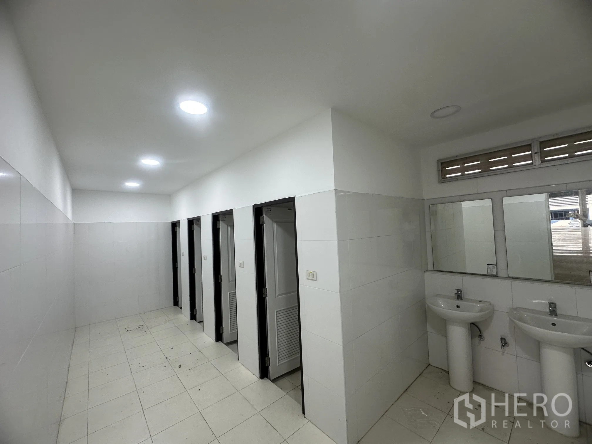 Factory for rent in Bang Phli, Samut Prakan - Clean tiled restroom with multiple stalls, sinks, and mirrors.