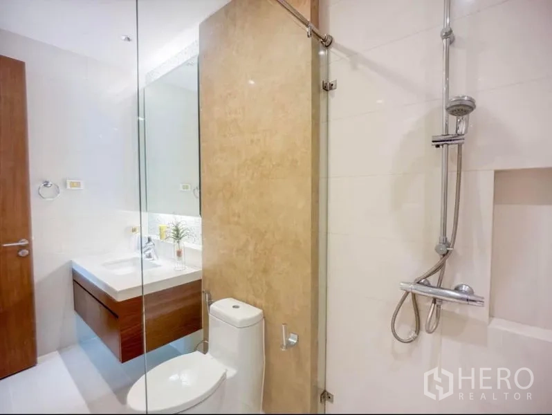 Condominium for rent in Khlong Toei, Bangkok - Close-up of the shower zone with handheld shower, glass door and view toward the vanity.