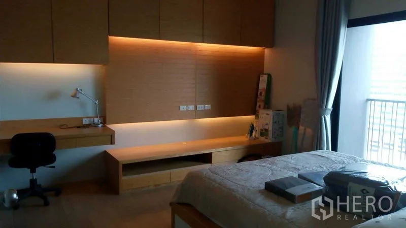 公寓 出租在Watthana, Bangkok - 卧室内置书桌与储物柜，暖色灯带，临近阳台。