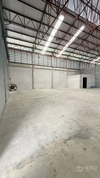 货栈 出租在Min Buri, Bangkok - 从卷帘门方向拍摄，通风百叶、高杆灯与开阔地面一览无余。