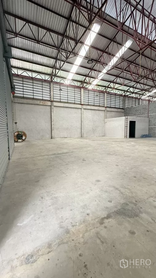 货栈 出租在Min Buri, Bangkok - 从卷帘门方向拍摄，通风百叶、高杆灯与开阔地面一览无余。