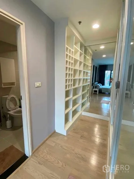 Condominium for rent in Khlong Toei, Bangkok - Corridor with floor-to-ceiling shelving, mirror doors and access to bathroom and bedroom.