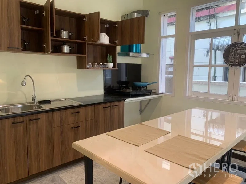 Home Office for rent in Suan Luang, Bangkok - Kitchen with wood cabinetry, sink, gas hob, extractor and central island.
