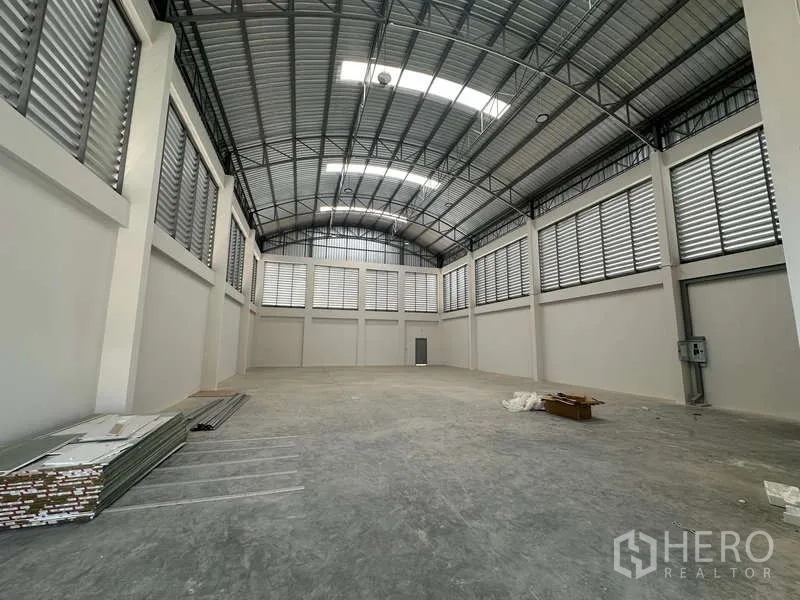 工厂 出售在Lam Luk Ka, Pathum Thani - 纵深仓库视角，钢屋顶、电箱与大面积地面。