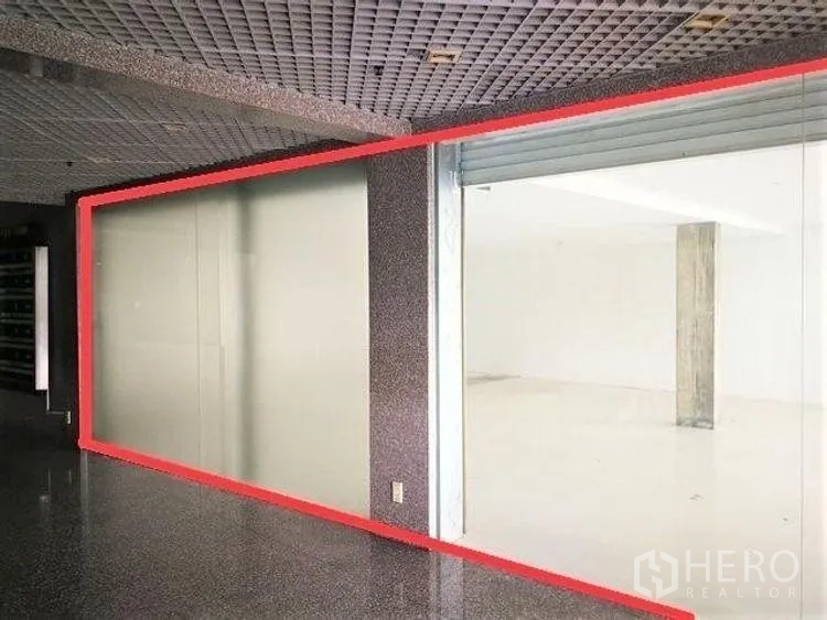 零售空间 出租在Phaya Thai, Bangkok - 走廊视角的店铺，宽大玻璃门面与卷帘门