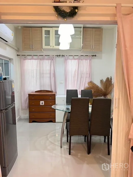 Detached House for rent - Secondary dining nook with glass table, pendant light, tall fridge and soft curtains.
