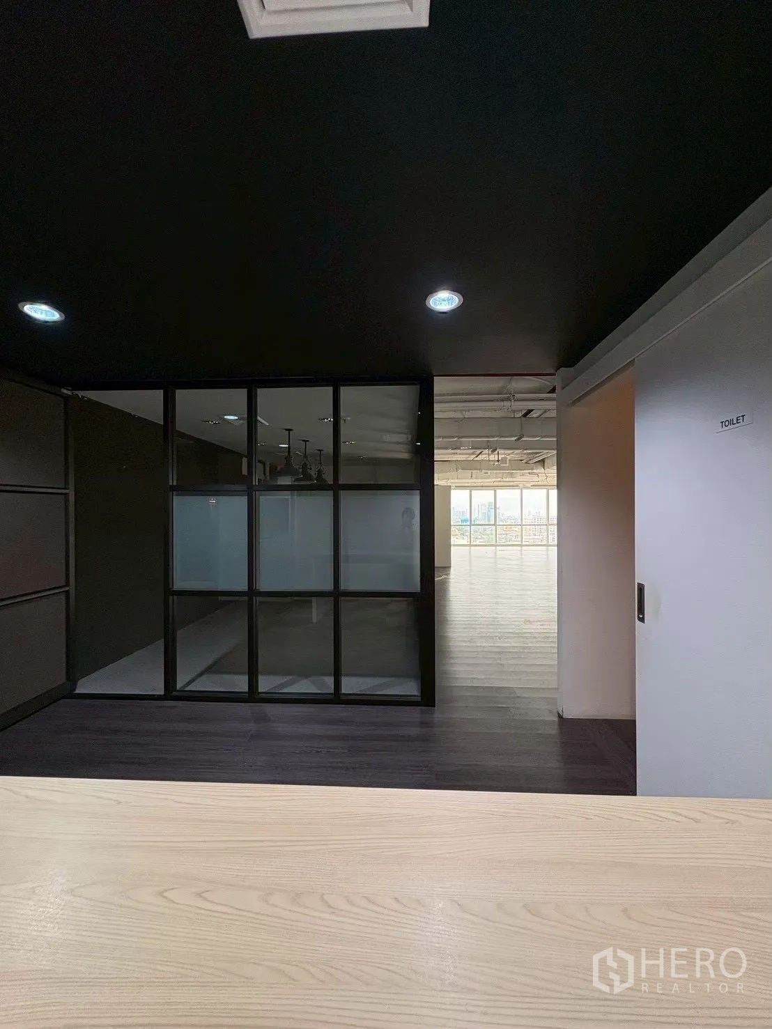 Office Space for rent in Khlong Toei, Bangkok - View from the reception toward a glass-partitioned room and open workspace.