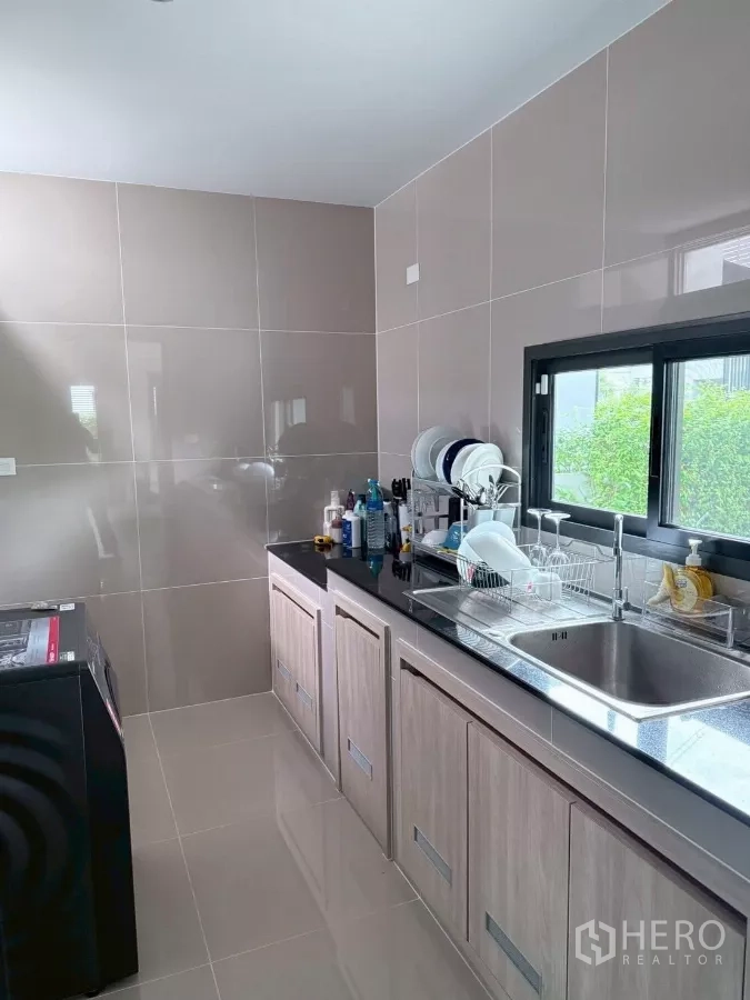 Detached House for rent in Lat Krabang, Bangkok - Separate Thai kitchen with tiled walls, black stone countertop and stainless sink.