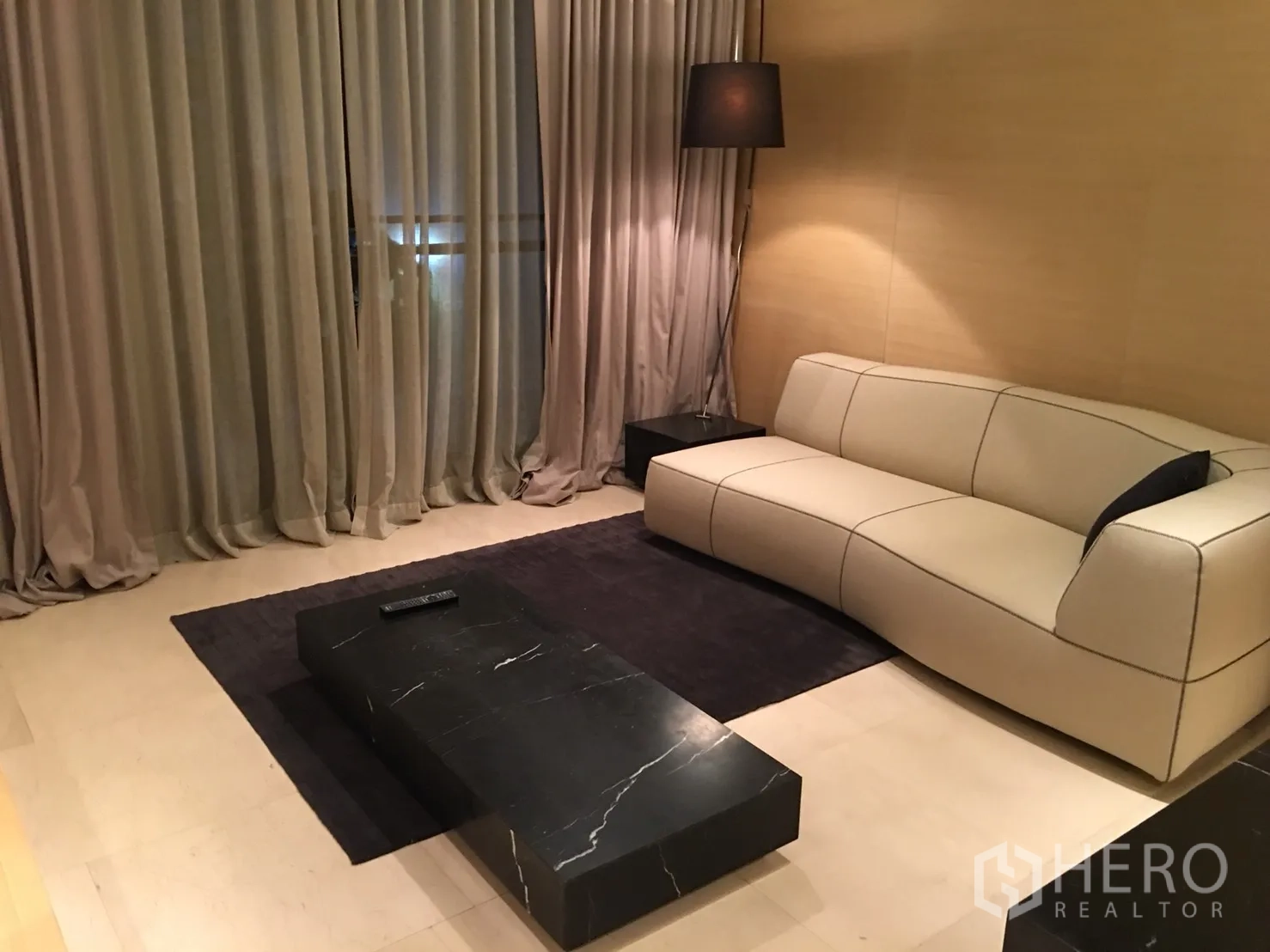 Condominium for rent or sale in Bang Rak, Bangkok - Contemporary living room featuring cream sofa, black marble coffee table and floor lamp.