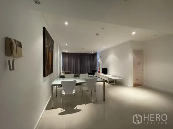 Condominium for rent or sale in Watthana, Bangkok - View from entry to dining and living zones with minimalist decor, recessed lighting, and neutral tile floors.