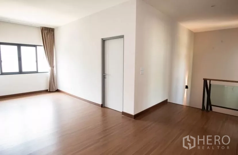 Detached House for rent in Bang Phli, Samut Prakan - Upper floor landing with wood floors, natural light and a white door.