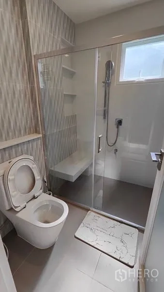 Detached House for rent in Prawet, Bangkok - Modern bathroom with glass-enclosed shower, wall niches and toilet.