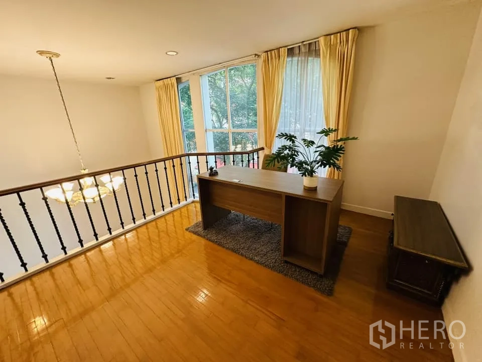 联排别墅 出租在Watthana, Bangkok - 夹层书房俯瞰客厅，大片窗帘与吊灯营造通透感