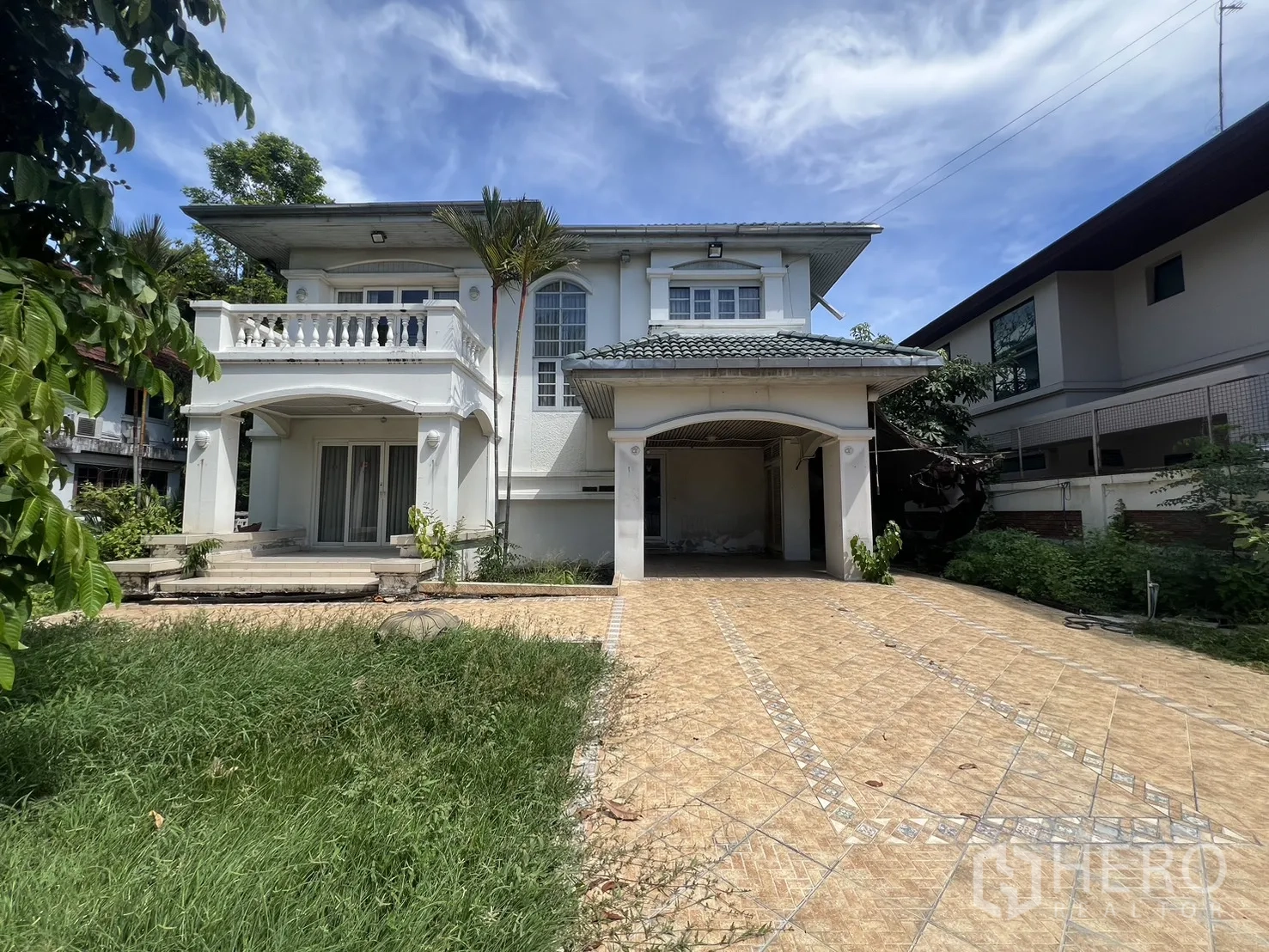 Detached House for sale in Saphan Sung, Bangkok - Front facade of two-storey house with carport, balcony, and paved driveway.
